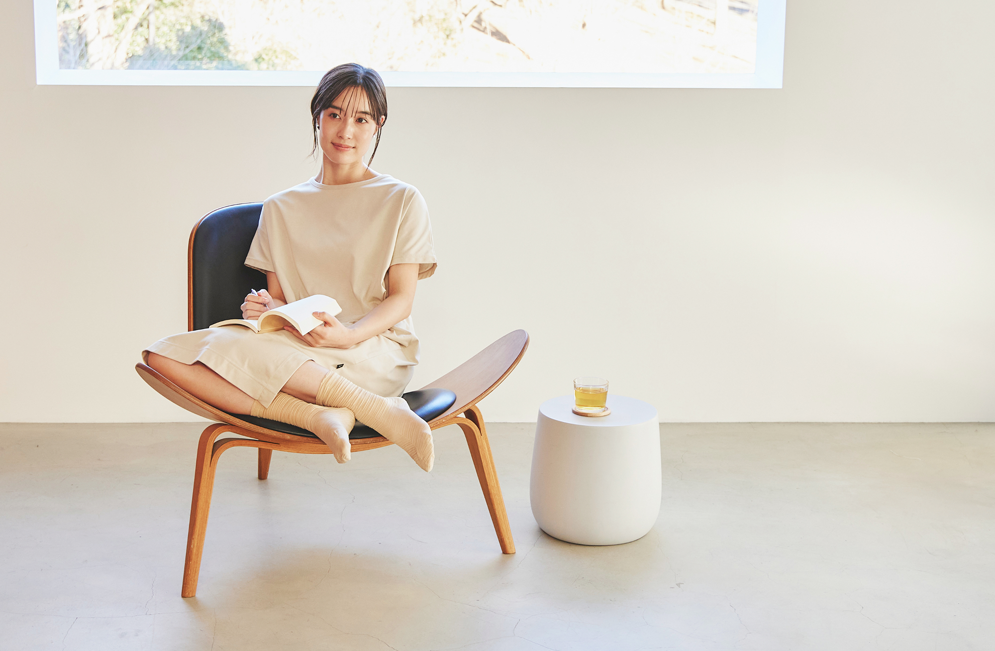 椅子に腰かけて本を読みながらくつろぐ女性