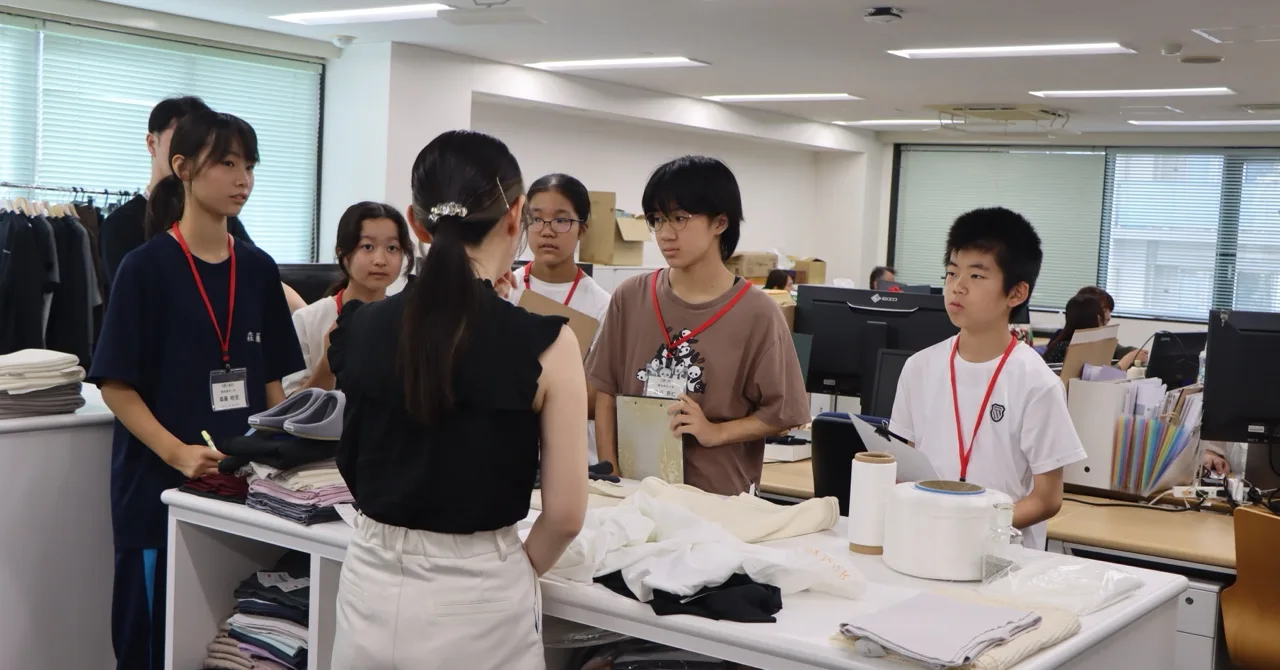 オフィスフロアで商品企画部の社員から説明を受ける生徒たち