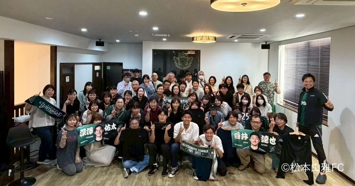 現地参加者と選手たちの集合写真。松本山雅FCのタオルマフラーを掲げる参加者も